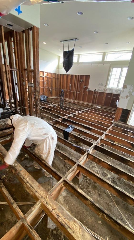 Damaged room with wet flooring and lower walls removed